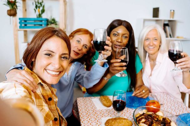 Mulheres de diferentes idades brindando em uma refeição social para artigo sobre interação social
